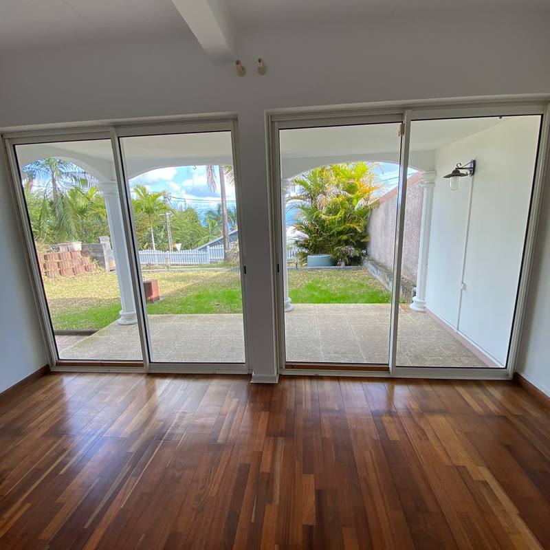 Pièce vide au parquet, deux baies vitrées ouvrant sur un jardin