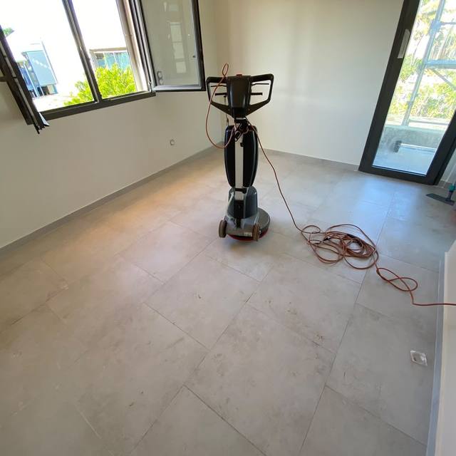 Monobrosse sur le carrelage d’une pièce vide, câble déroulé