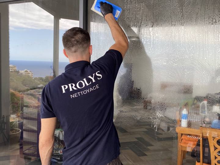 Intervenant Prolys nettoyant une grande baie vitrée avec une raclette