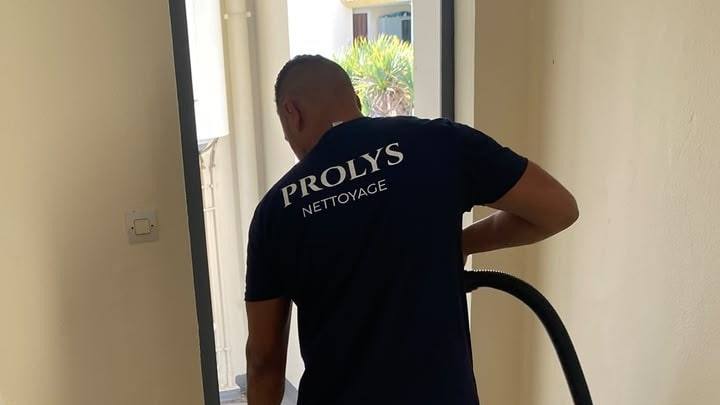 Intervenant Prolys, de dos, en tee-shirt Prolys Nettoyage, passant l’aspirateur dans un logement