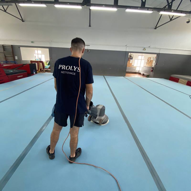 Intervenant Prolys nettoyant un sol sportif à la monobrosse à Saint-Pierre